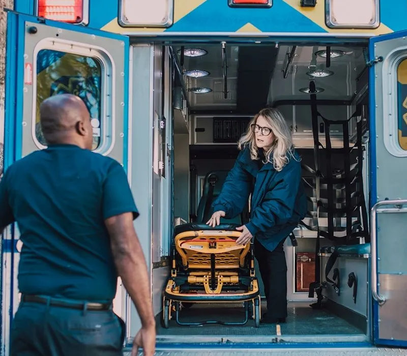 EMS crew loading a stretcher into the back of an ambulance